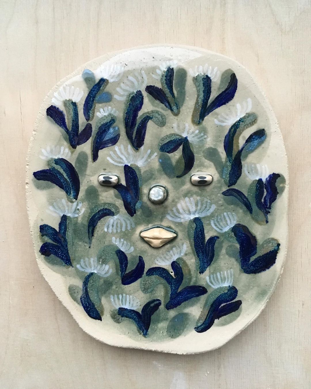 Ceramic face with plant motif