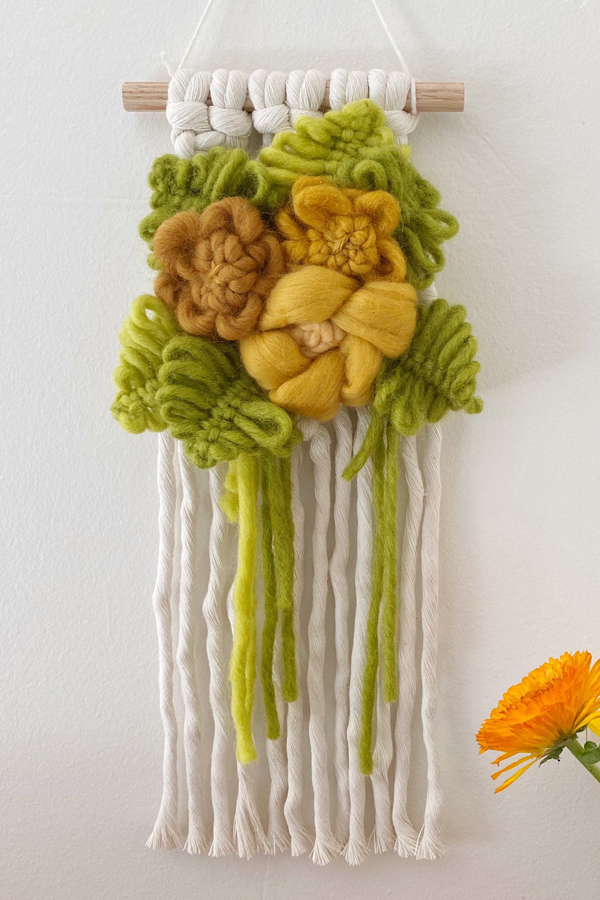 Modern macrame wall hanging with yarn flowers