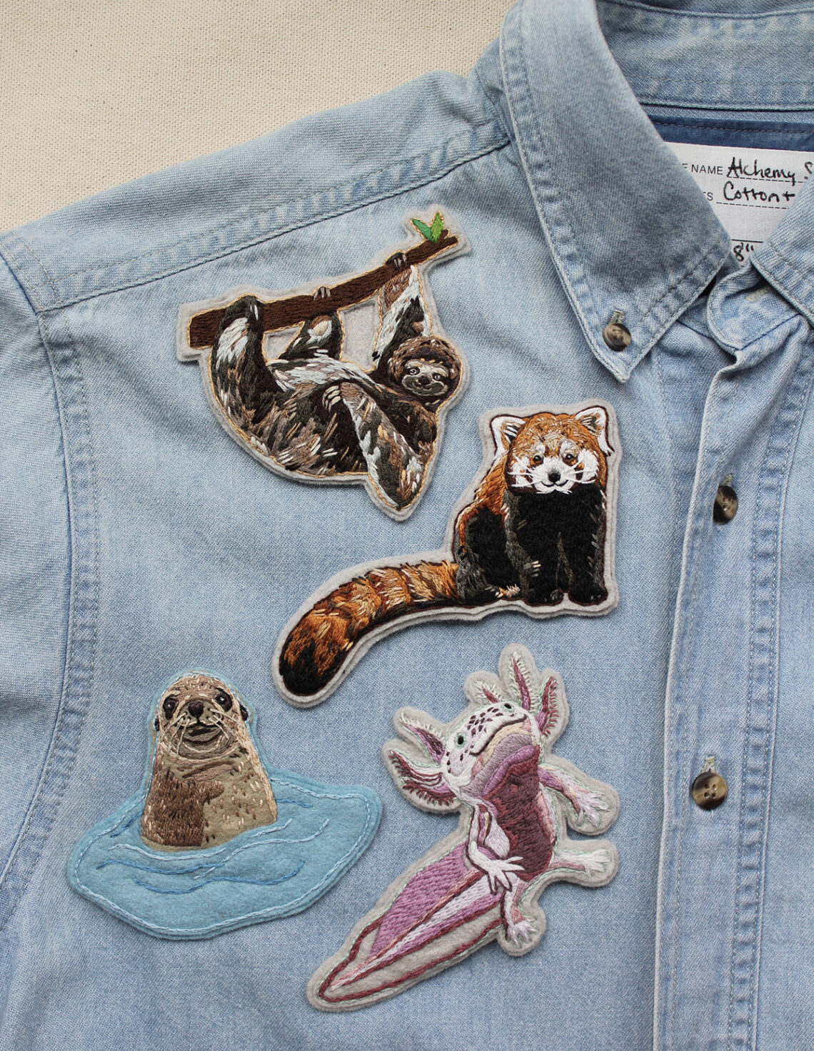 Sloth patch, red panda patch, sea lion patch, and an axolotl patch on a denim shirt